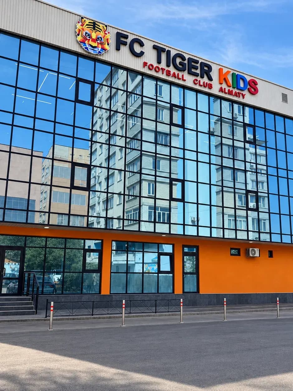 Здание филиала на Толе би: стеклянный фасад с вывеской FC Tiger Kids